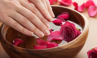 Hände in Schale mit Rosenblättern und Wasser